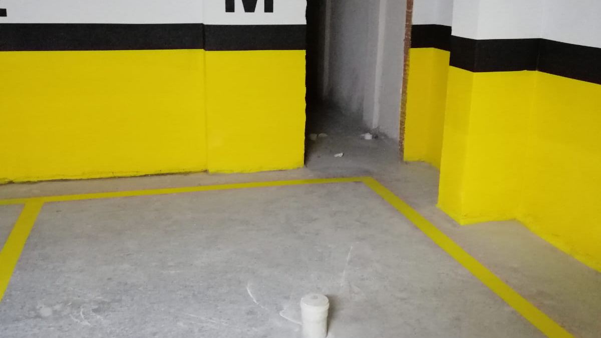 Kapalı otoparkta sarı duvar bantları ve silinmiş beton zemin